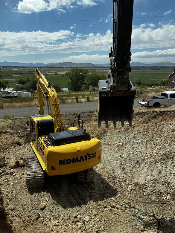 Two excavators cutting a hillside pad above the valley