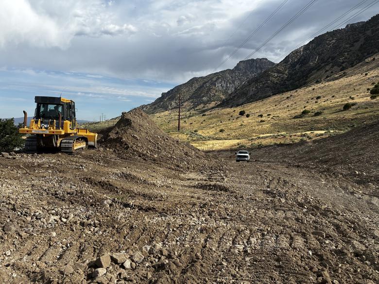 A dozer pushing spoil across a graded hillside