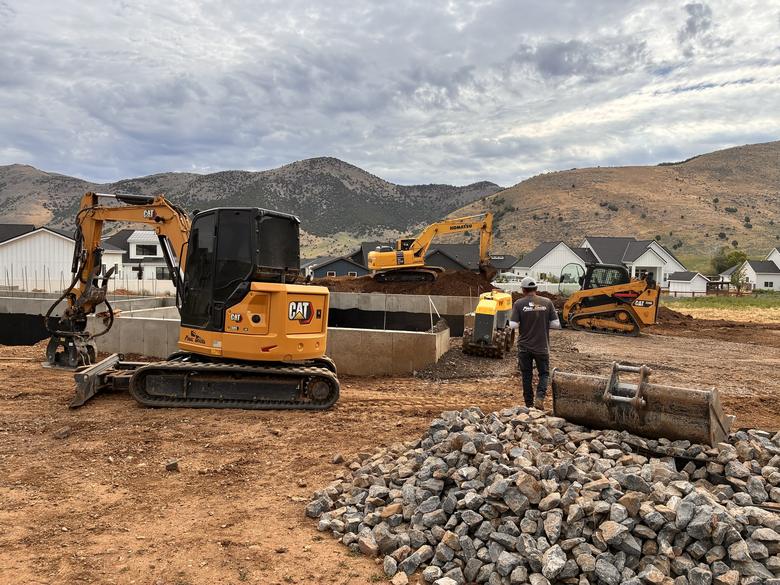 The crew and machines working around a poured foundation