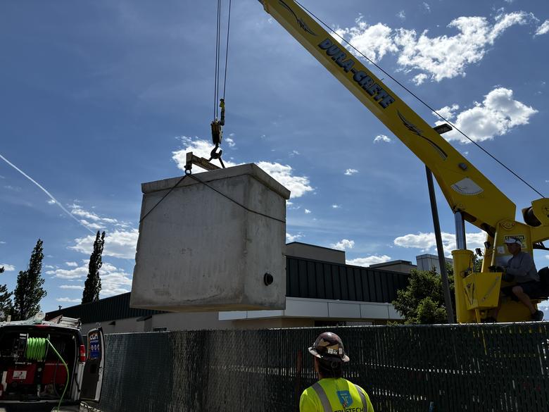 A crane setting a large precast concrete vault into the ground