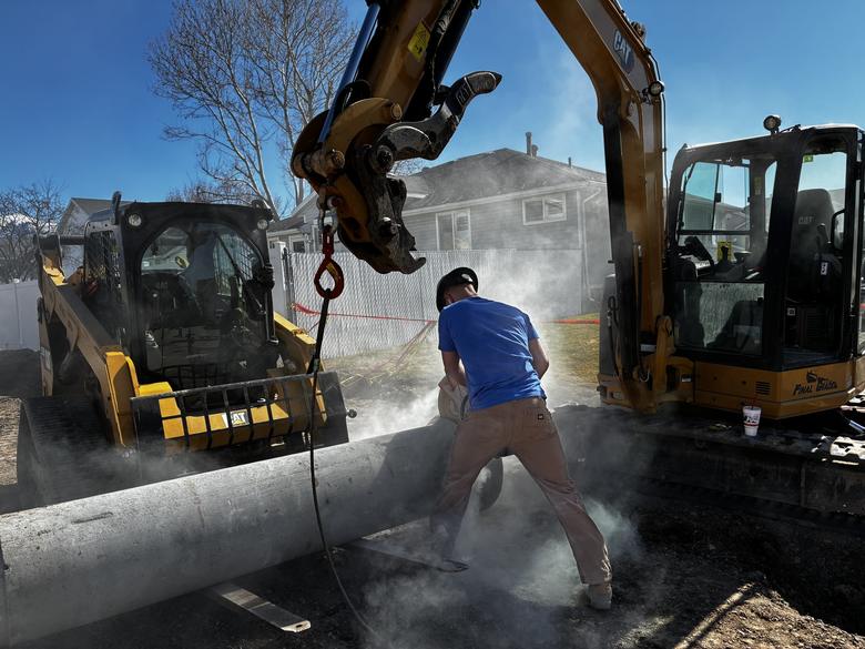 Cutting a large concrete pipe to length between two machines
