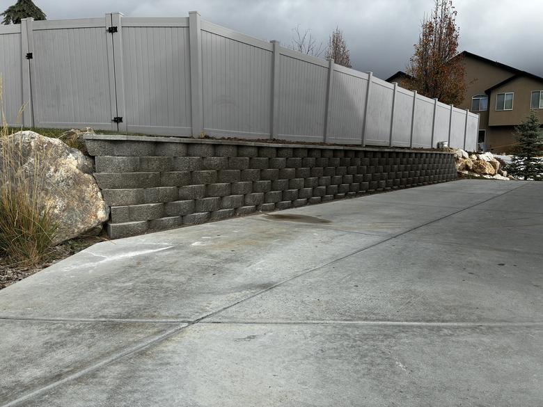 A finished block retaining wall running along a driveway