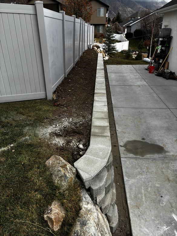 A capped block wall curving into a boulder edge